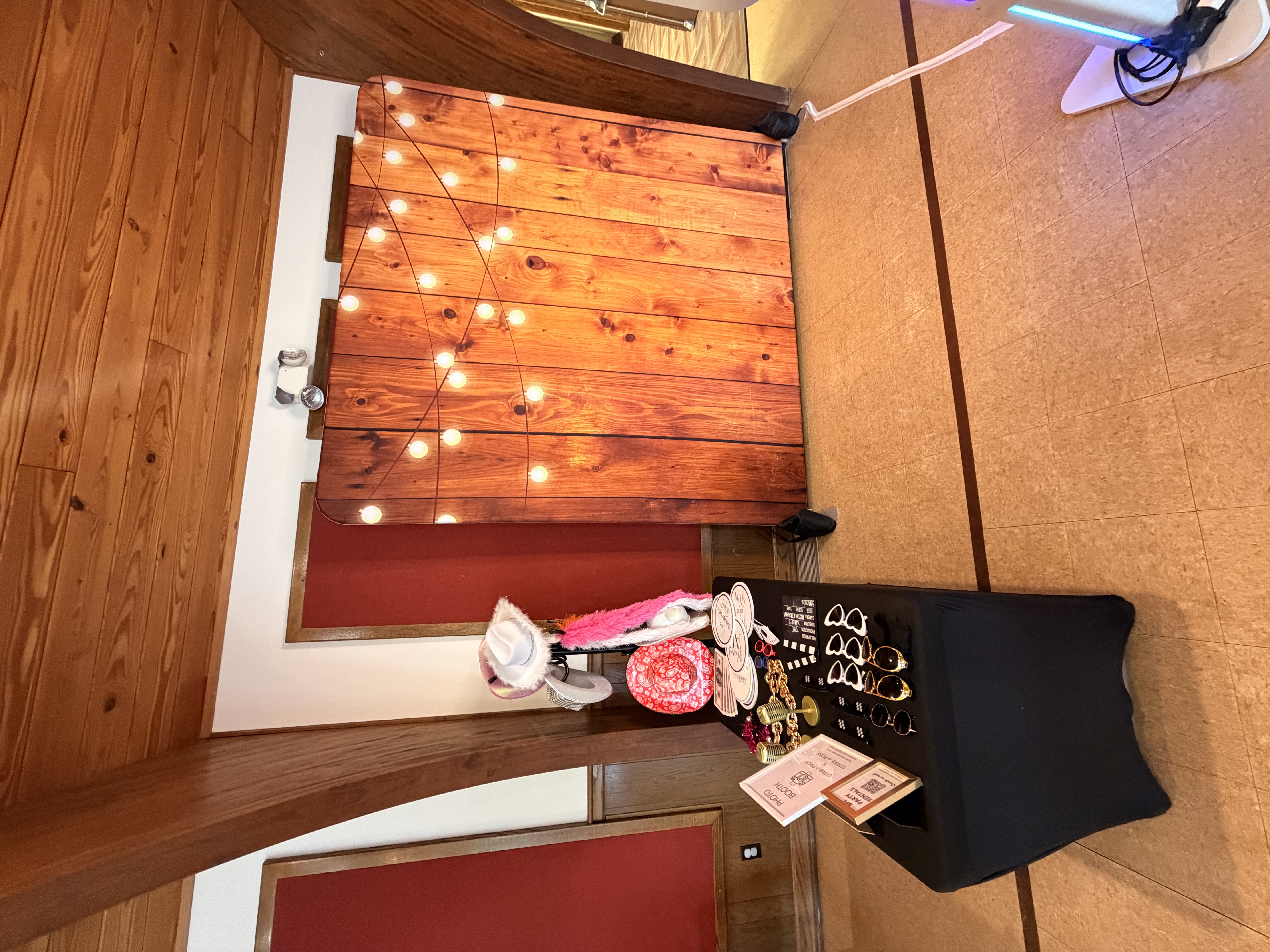 Rustic wood marquee-bulb backdrop with a prop table